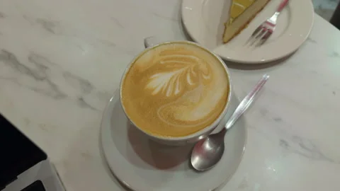 Stylish marble table with latte and cake. Artistic arrangement of latte and cake Stock Footage 333908458