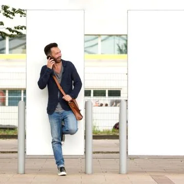Stylish mature guy using mobile phone outdoors on street Stock Photos