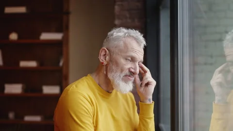 Stylish mature man feeling upset while looking out the window, personal problems Stock Footage 340903138