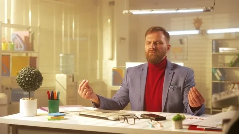 A stylish middle aged man with a beard relaxes in a zen pose. A businessman in a Stock Footage 238506138
