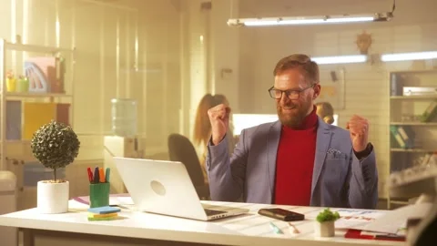 A stylish middle aged man with a beard looks through information on a laptop Stock Footage 238506244