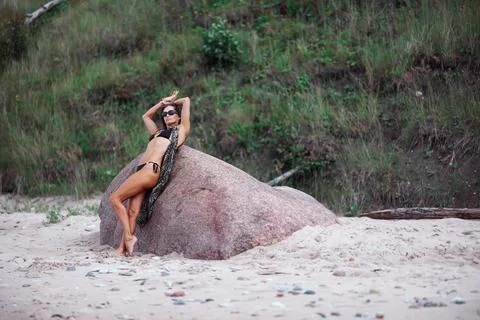 A Stylish Model is Gracefully Posing on a Rock at the Beautiful Beach, Radiating Stock Photos