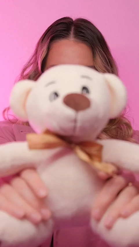 A stylish model poses in vibrant pink attire with sunglasses, holding a plush Stock Footage 311572228