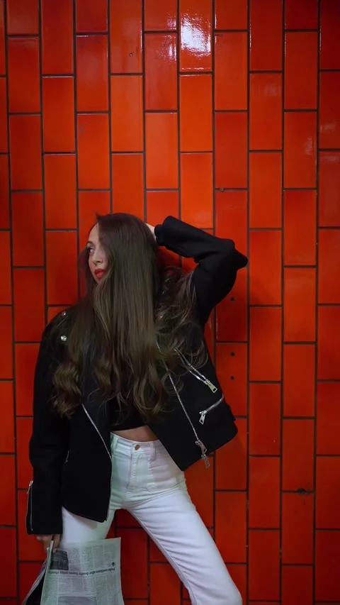Stylish Model is Posing Elegantly Against Vibrantly Colored red Wall Vidéo 291615447