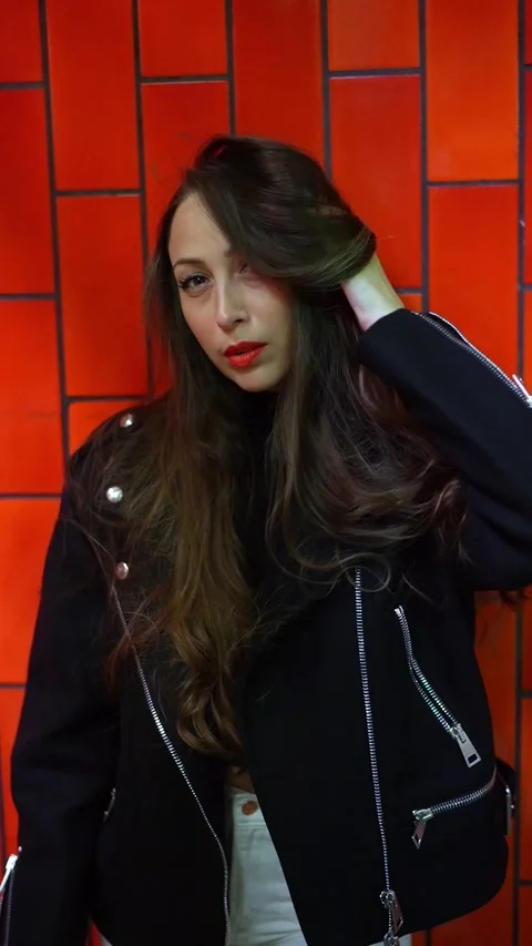 Stylish Model is Posing Elegantly Against Vibrantly Colored red Wall Vidéo 295070538