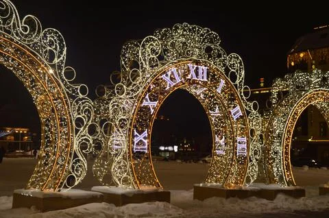 Stylish New Year's luminous clock and arch with garlands. Christmas city il.. Stock Photos