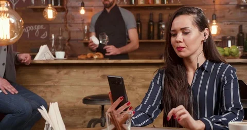 Stylish ,nice looking woman using her smartphone and headphones while engaged in Stock Footage 103373618