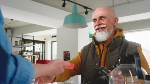 A stylish old man makes a purchase in a coffee shop, pays with a bank card Stock Footage 246901743