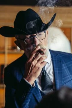 Stylish old man in wide brimmed hat and rich blue mens suit smok Stock Photos