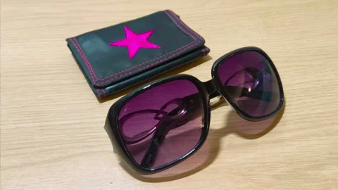 Stylish oversized sunglasses and a chic wallet with a vibrant pink star emblem Video stock 318610901