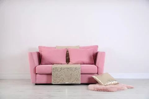 Stylish pink sofa against white wall in modern living room interior. Space fo Stock Photos