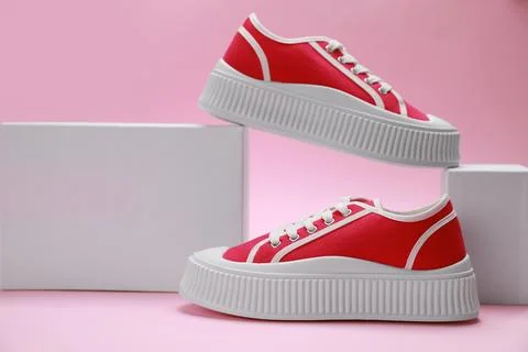 Stylish presentation of red classic old school sneakers on pink background Stock Photos