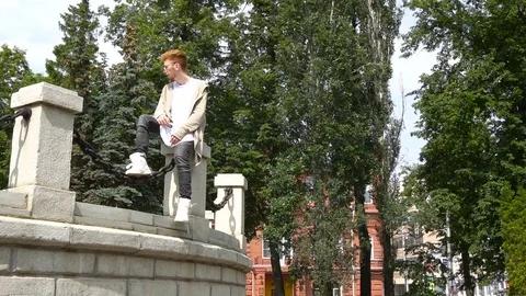 Stylish redhead man relaxing in the park. Summer Stock Footage 78964355