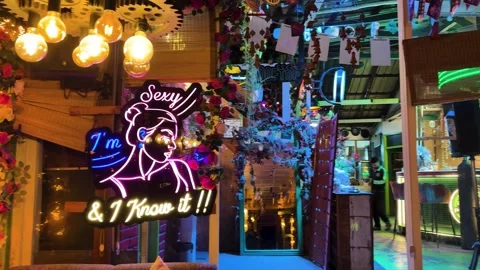 Stylish restaurant interior with illuminated neon sign and hanging vintage bulbs Stock Footage 336538010