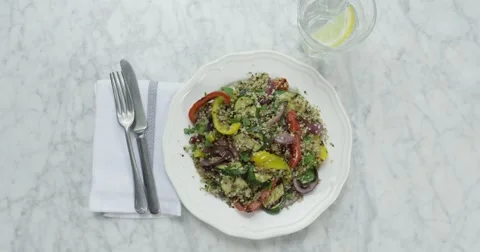 Stylish Roast Vegetable Cous Cous with knife, fork, glass of lemon water. Video stock 63927234