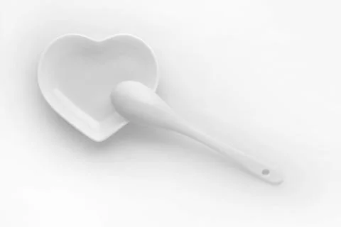 Stylish romantic tableware. Ceramic glossy spoon on a plate in the form of a  Stock Photos