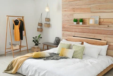 Stylish room interior with comfortable bed near wooden wall Stock Photos