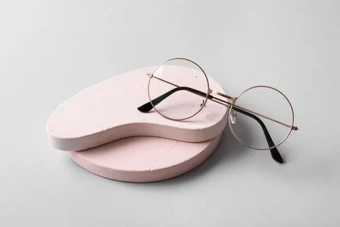 Stylish round eyeglasses with rose gold frames on pink concrete pedestals, mo Stock Photos
