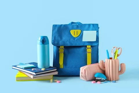 Stylish school backpack with different stationery and bottle of water on blue Stock Photos
