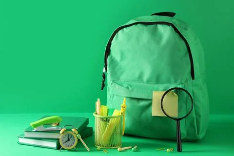 Stylish school backpack with different stationery, magnifying glass and alarm Stock Photos