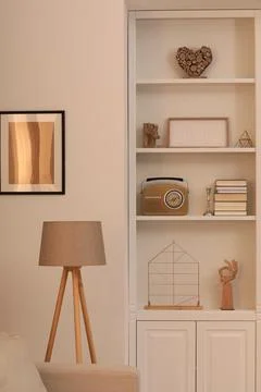 Stylish shelves with different decor elements and lamp in room. Interior desi Stock Photos
