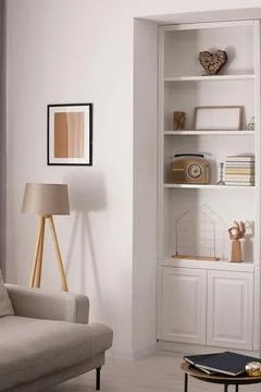 Stylish shelves with different decor elements and lamp in room. Interior desi Foto stock