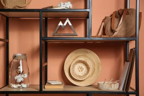 Stylish shelving unit with decorative elements near color wall. Interior desi Stock Photos