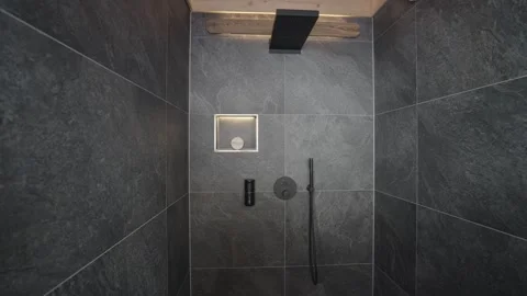 Stylish shower cubicle with black matte fixtures, slate tiles, and warm ambient 스톡 동영상 335756934