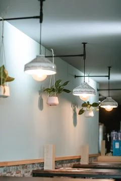 Stylish side view of a bar featuring designer white lamps, hanging plants, .. Stock Photos
