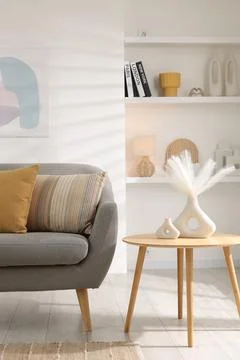 Stylish sofa with cushions and decor elements on side table in living room... 写真素材