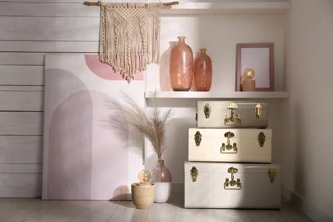 Stylish storage trunks and different decor elements near white wall indoors.  Stock Photos