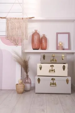 Stylish storage trunks and different decor elements near white wall indoors.  Stock Photos