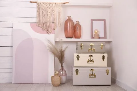 Stylish storage trunks and different decor elements near white wall indoors.  Stock Photos