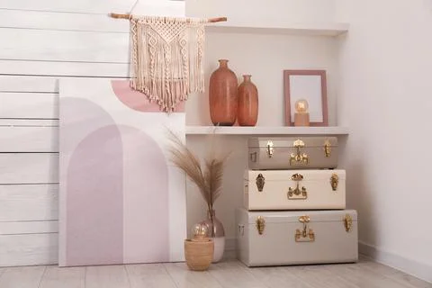 Stylish storage trunks and different decor elements near white wall indoors.  Stock Photos