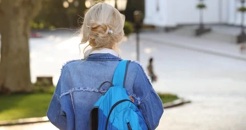 Stylish student with blue backpack in denim jacket walks 動画素材 113519616