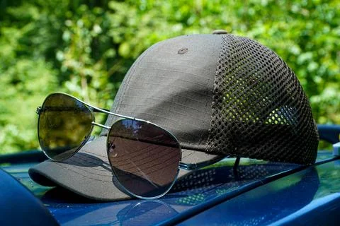 Stylish sunglasses on a gray cap visor, summer sunglasses composition Stock Photos
