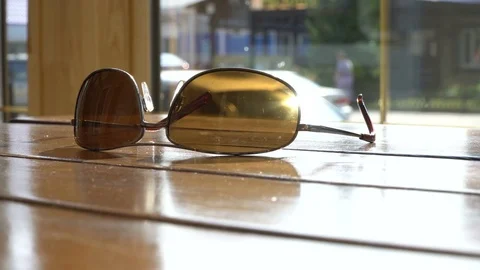 Stylish sunglasses lying on the table in cafe. Sunny summer street background 4k 스톡 동영상 80787774