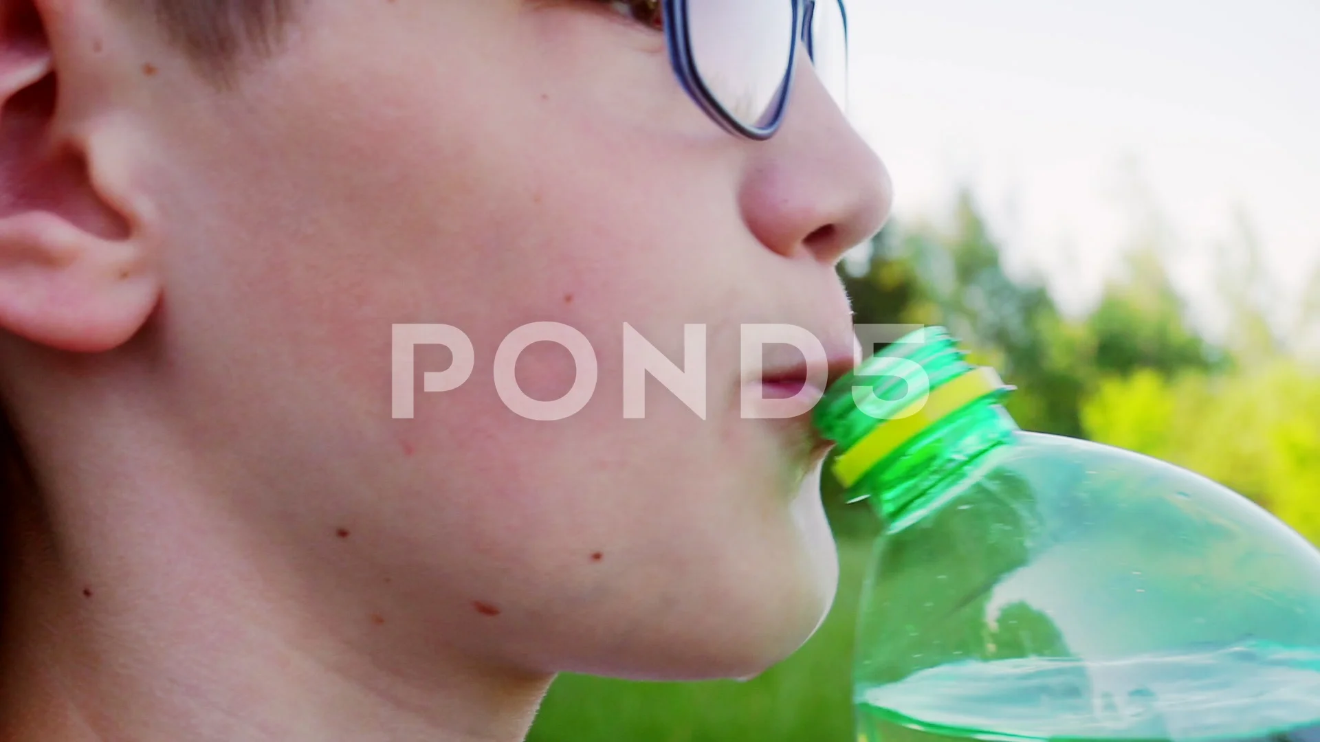 Teen boy drinks water from a bottle, Stock Video