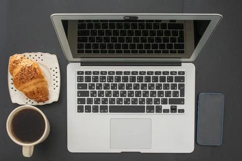 A stylish top-down view of a workspace featuring a laptop, coffee, croissan.. Stock Photos