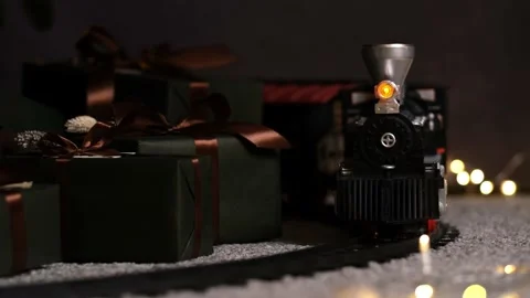 Stylish toy train rides reverse under Christmas tree with many gift boxes Stock-Footage 165947865