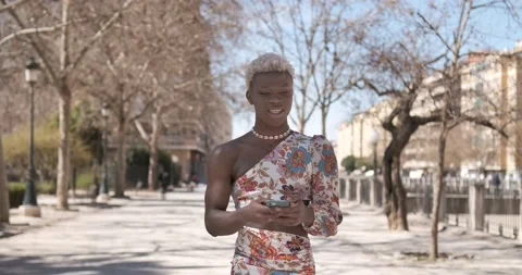Stylish transgender person smiling while using a mobile phone walking outdoor Stock-Footage 239462813