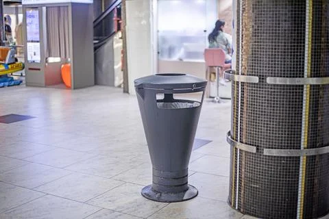 A stylish triangular trash can near a wall in a shopping center Stock Photos