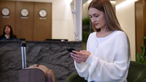 Stylish tripper texting in modern hotel lobby during evening check-in Stock Footage 276151729