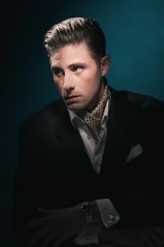 Stylish Vintage fashion dandy young man with scarf in suit. Against dark blue Stock Photos
