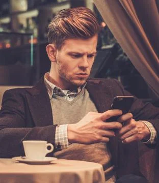 Stylish wealthy man using mobile phone in a restaurant. Stock Photos