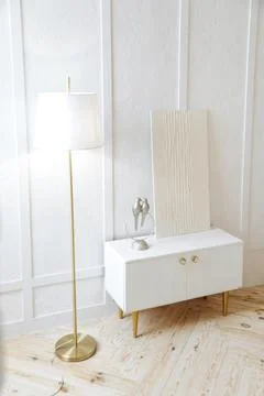 Stylish white bedside table with decor, floorlamp and white abstract gypsum Stock Photos