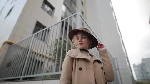 Stylish woman in hat posing for camera against the background of the city Stock Footage 143166925