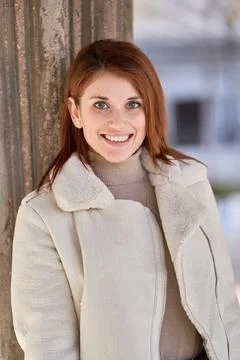 Stylish woman with jacket smiling while standing outdoors. Foto stock