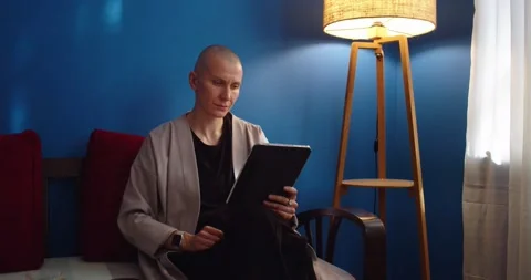 Stylish woman sitting on couch using ipad and reading by lamplight in evening Stock Footage 200803571