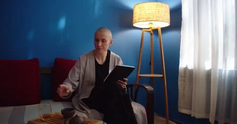 Stylish woman sitting on sofa using ipad and drinking tea at home in evening Stock Footage 200084111